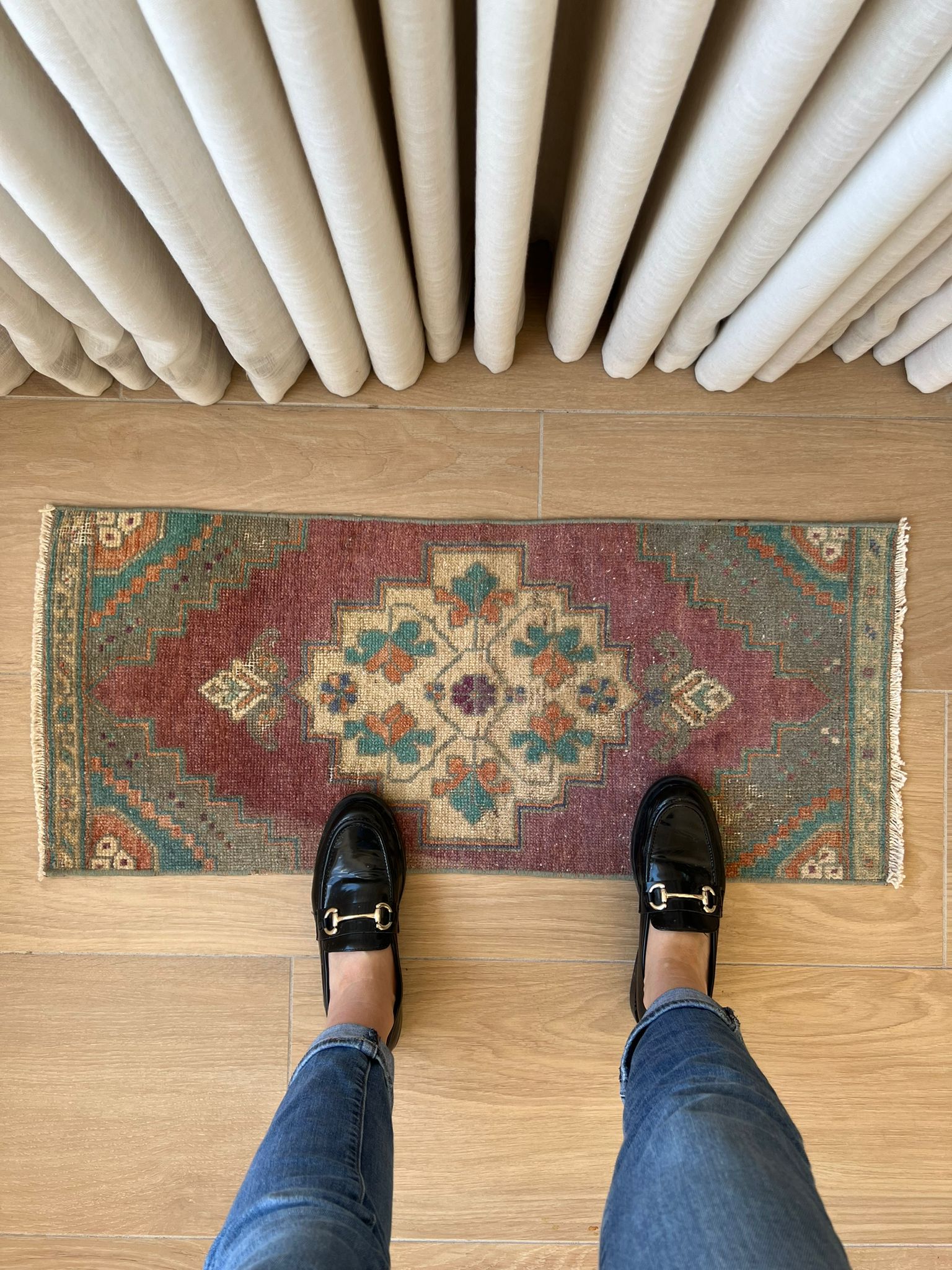 Add a pop of colour with vintage flair! Our vintage Turkish traditional distressed mini rug features greens, blues, purples, orange, taupes, and wine hues, with a tribal and Aztec central motif design. Hand-knotted and uniquely vintage, this antique rug adds timeless sophistication to your space, inspired by design styles reminiscent of Studio McGee and Amber Interiors. Perfect for bathmats, kitchen mats, or door entries