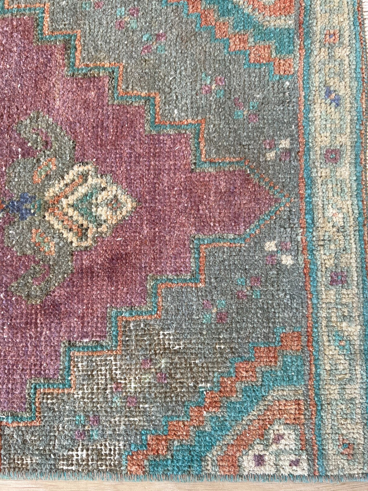 Add a pop of colour with vintage flair! Our vintage Turkish traditional distressed mini rug features greens, blues, purples, orange, taupes, and wine hues, with a tribal and Aztec central motif design. Hand-knotted and uniquely vintage, this antique rug adds timeless sophistication to your space, inspired by design styles reminiscent of Studio McGee and Amber Interiors. Perfect for bathmats, kitchen mats, or door entries